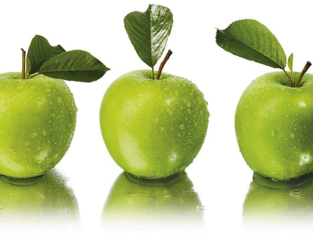 Fototapeta z trzema zielonymi jabłkami z kroplami wody i liśćmi