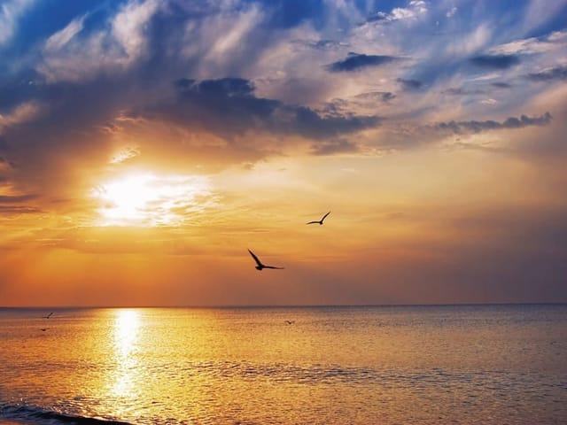 Fototapeta Zachód słońca nad spokojnym morzem (kod: 12143) Fototapeta z zachodem słońca nad morzem, pomarańczowe niebo i chmury