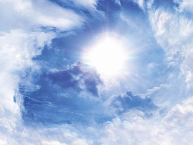 Fototapeta z jasnym słońcem na niebie, otoczonym białymi chmurami