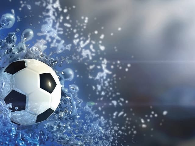 Fototapeta z piłką nożną i rozpryskującą się wodą na niebieskim tle