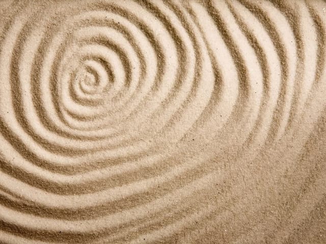 Fototapeta z koncentrycznymi wzorami na piasku, podkreślona cieniami