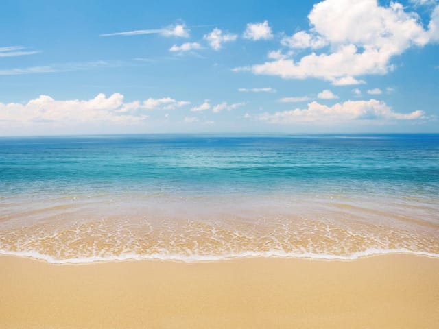 Fototapeta z piaszczystą plażą, spokojnym morzem i błękitnym niebem