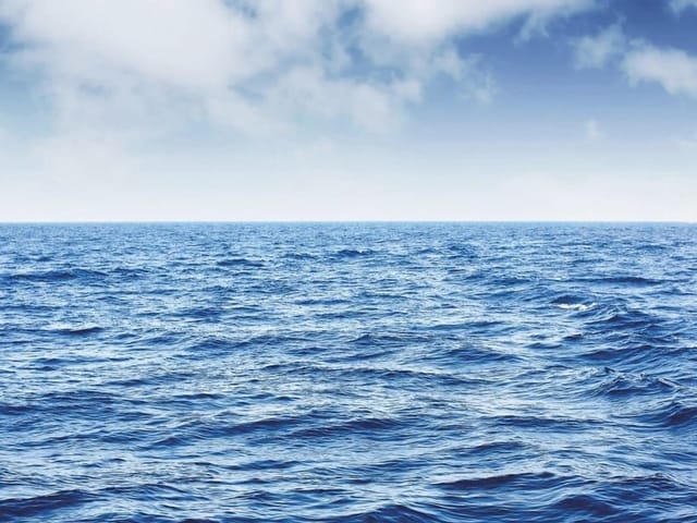 Fototapeta przedstawiająca rozległy ocean z błękitnym niebem i chmurami