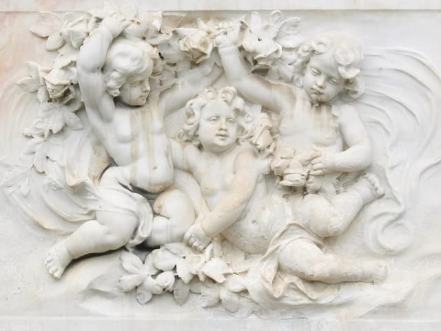 Fototapeta z płaskorzeźbą trzech puttów otoczonych kwiatami