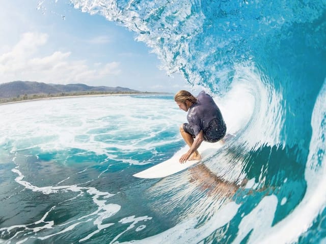 Fototapeta Surfer na fali przy brzegu (mpn: 2065) Fototapeta z surferem na desce, duża niebieska fala i białe grzywacze