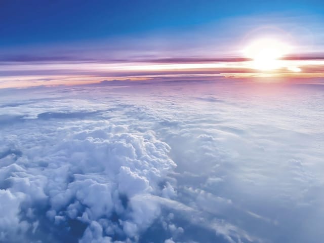 Fototapeta z chmurami oświetlonymi wschodzącym słońcem na niebieskim niebie