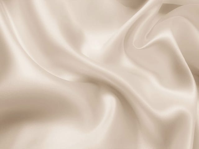 Fototapeta przedstawiająca falujący materiał z gładkimi fałdami i refleksami światła.