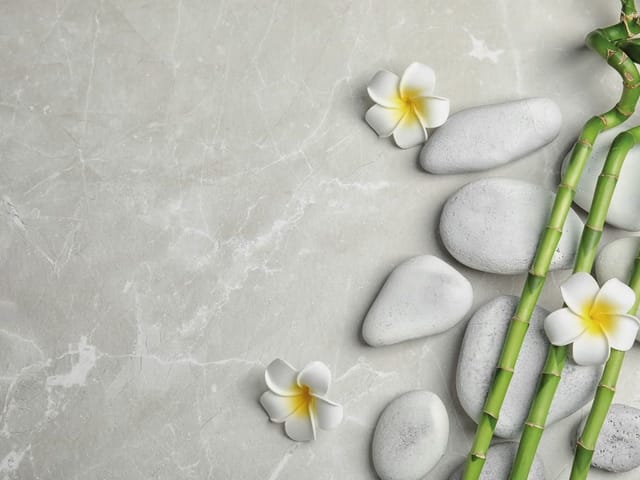 Fototapeta z szarymi kamieniami, bambusem i kwiatami plumerii na marmurze