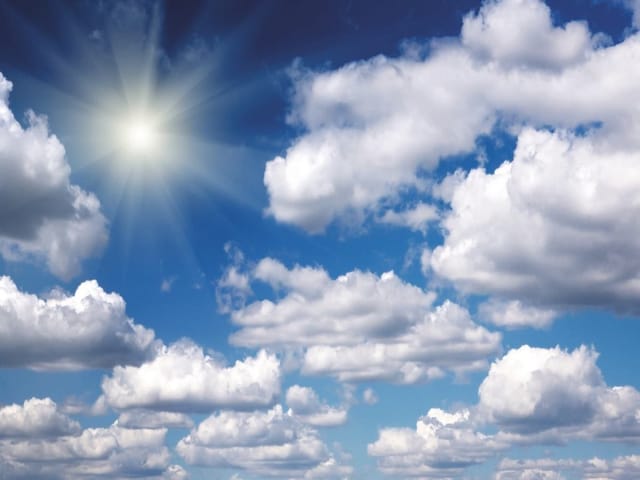 Fototapeta przedstawiająca jasne słońce i białe chmury na niebieskim niebie