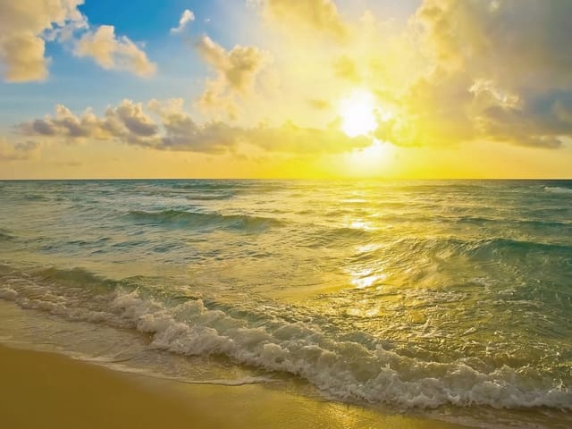 Fototapeta z zachodem słońca nad morzem, błękitnym niebem i piaszczystą plażą