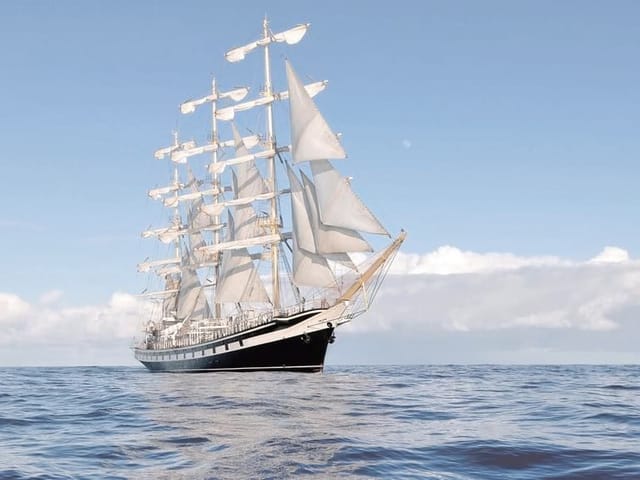Fototapeta przedstawiająca żaglowiec z białymi żaglami na oceanie pod jasnym niebem