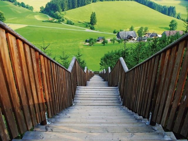 Fototapeta z drewnianymi schodami, zielonymi polami i lasami