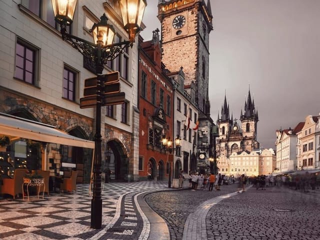 Fototapeta przedstawiająca zabytkową wieżę z zegarem, brukowaną ulicę i stylowe latarnie