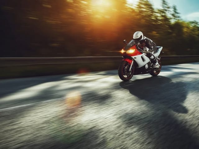 Fototapeta z motocyklem w ruchu na asfaltowej drodze z drzewami