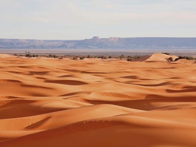 Fototapeta z rozległymi wydmami pustynnymi i odległymi górami