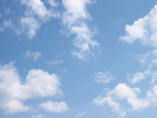 Fototapeta z błękitnym niebem i rozproszonymi białymi chmurami, lekko zamglonymi