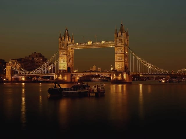 Fototapeta przedstawiająca oświetlony most zwodzony z wieżami i wodą nocą