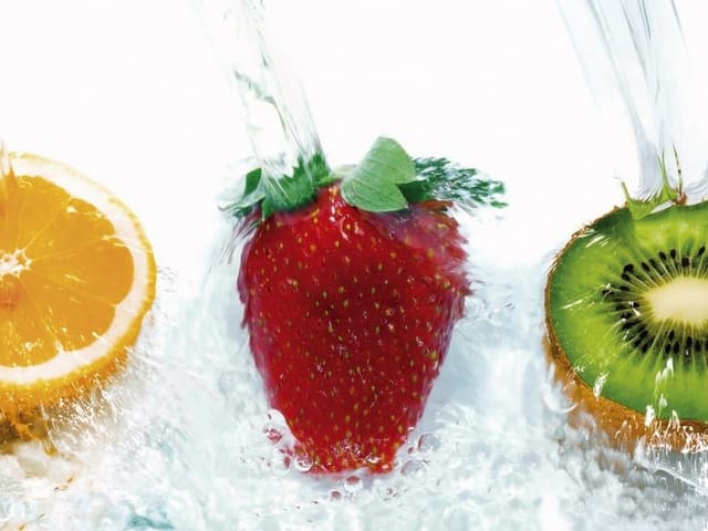 Fototapeta z pomarańczą, truskawką i kiwi w rozpryskującej się wodzie