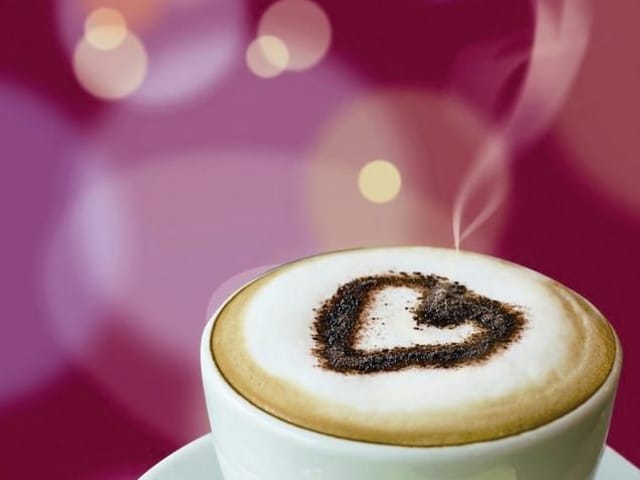 Fototapeta z filiżanką kawy z pianką i wzorem serca, rozmyte tło