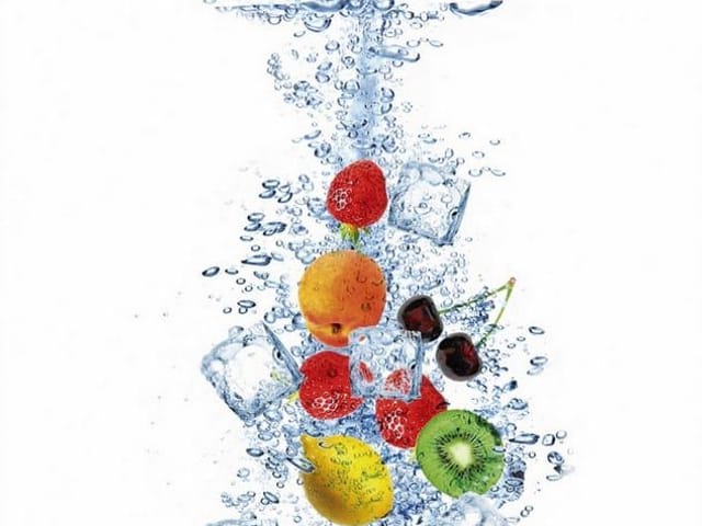 Fototapeta z owocami i kostkami lodu zanurzonymi w wodzie