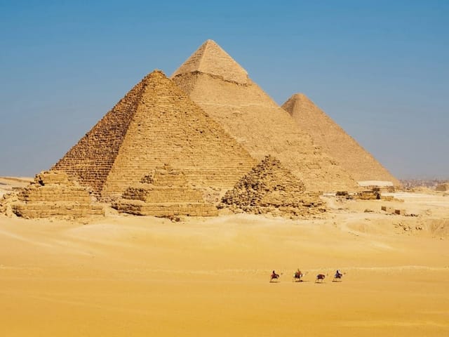 Fototapeta z trzema dużymi piramidami na rozległej pustyni i błękitnym niebie