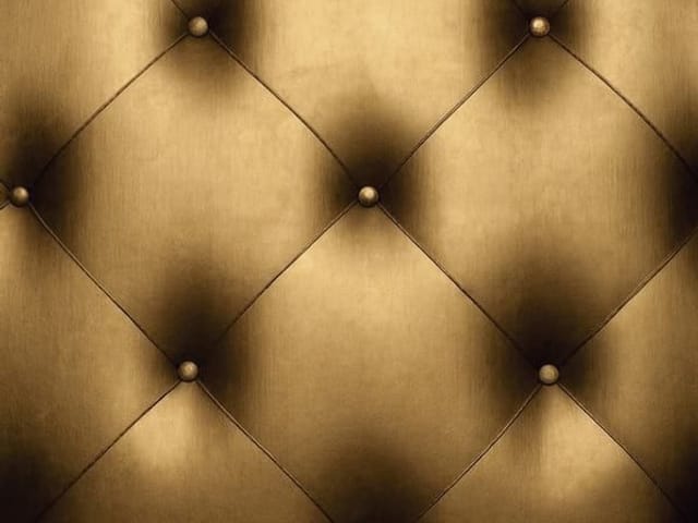 Fototapeta z pikowaną powierzchnią w złotym kolorze i metalicznymi guzikami