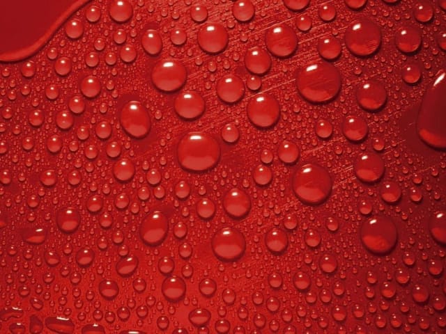 Fototapeta z kroplami wody na czerwonym tle, różne rozmiary kropel