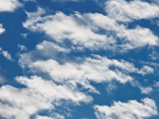 Fototapeta z białymi chmurami na tle niebieskiego nieba, rozproszone obłoki