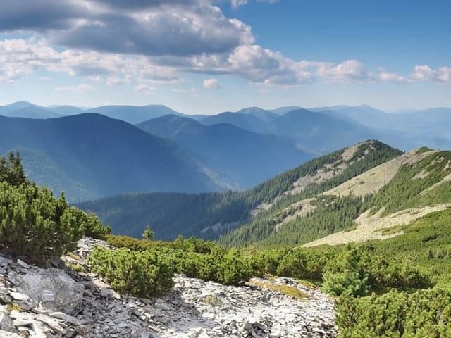 Fototapeta z zielonymi wzgórzami i pasmem górskim w tle
