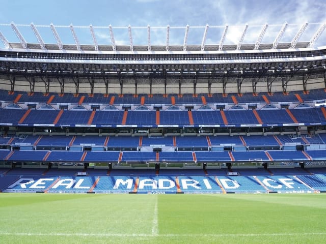 Fototapeta przedstawiająca pusty stadion piłkarski z niebieskimi trybunami