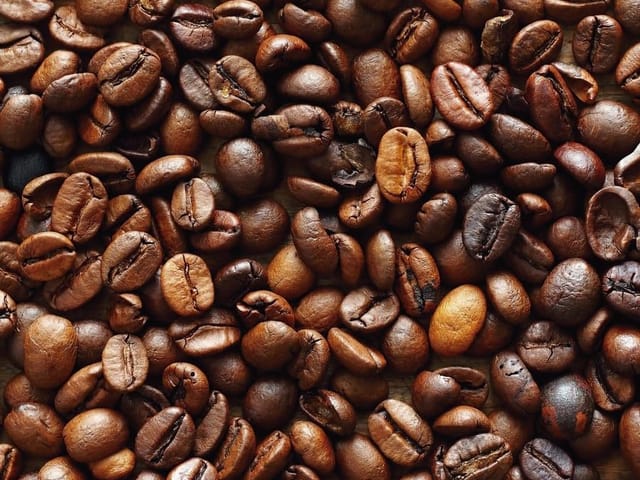 Fototapeta z ziarnami kawy w różnych odcieniach brązu, różne kształty i rozmiary