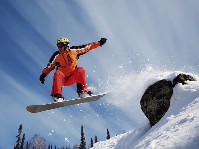 Fototapeta z osobą na snowboardzie w powietrzu nad śnieżnym stokiem