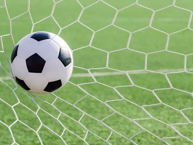 Fototapeta z piłką nożną w siatce bramki na tle zielonej murawy