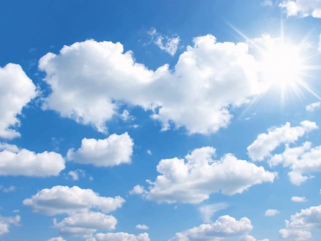 Fototapeta przedstawiająca białe chmury na błękitnym niebie z promieniami słońca