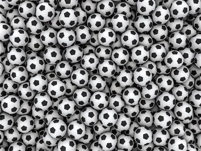 Fototapeta przedstawiająca stos czarno-białych piłek do piłki nożnej ułożonych blisko siebie