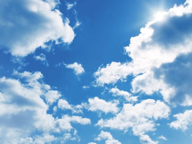 Fototapeta przedstawiająca niebo z białymi chmurami i słońcem za chmurami