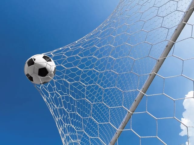 Fototapeta z piłką nożną wpadającą do siatki na tle nieba