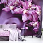 Miniatura fototapety Fioletowe orchidee na tkaninie we wnętrzu sypialni
