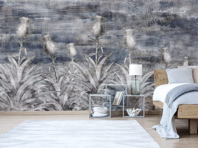 Fototapeta z wysokimi roślinami i kolczastymi kwiatami na tle chmurnego nieba