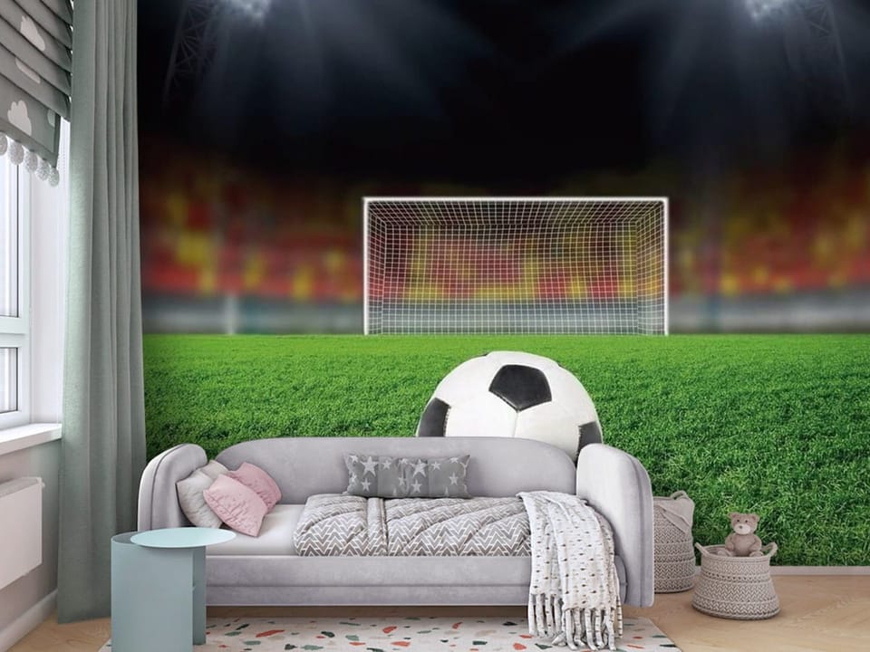 Fototapeta z piłką nożną na murawie stadionu z bramką i trybunami - ściana za kanapą w pokoju dziecka