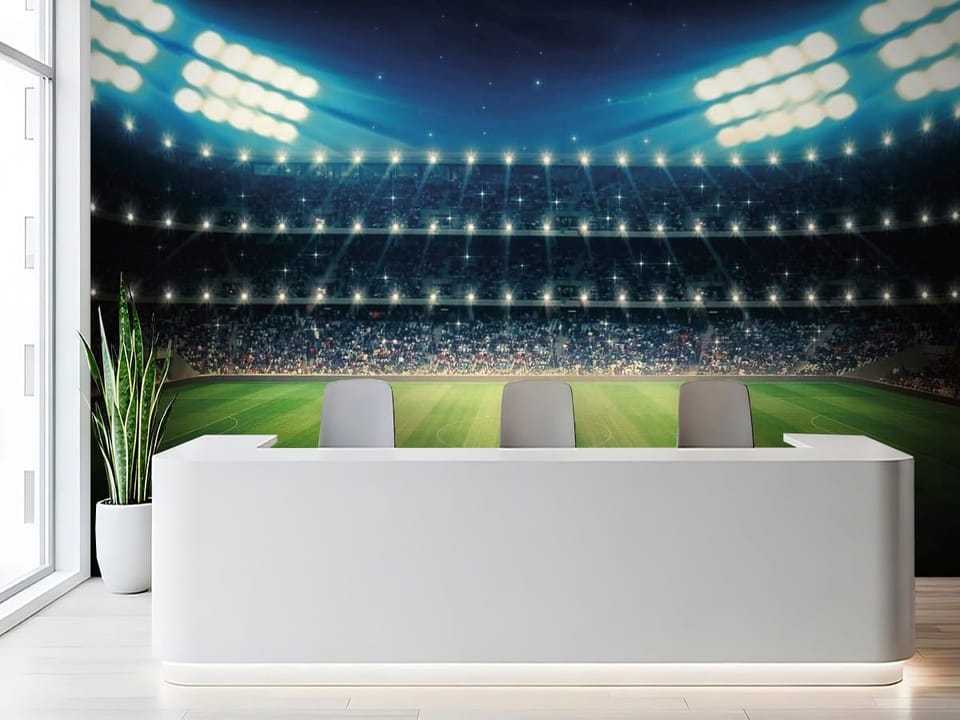 Fototapeta z oświetlonym stadionem piłkarskim nocą, zielona murawa i widzowie - aranżacja ściany w biurze za ladą recepcyjną