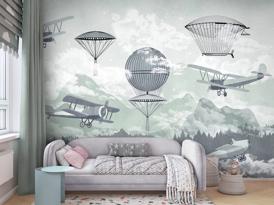 Fototapeta z balonami i samolotami nad górami i chmurami - ściana za kanapą w pokoju dziecka