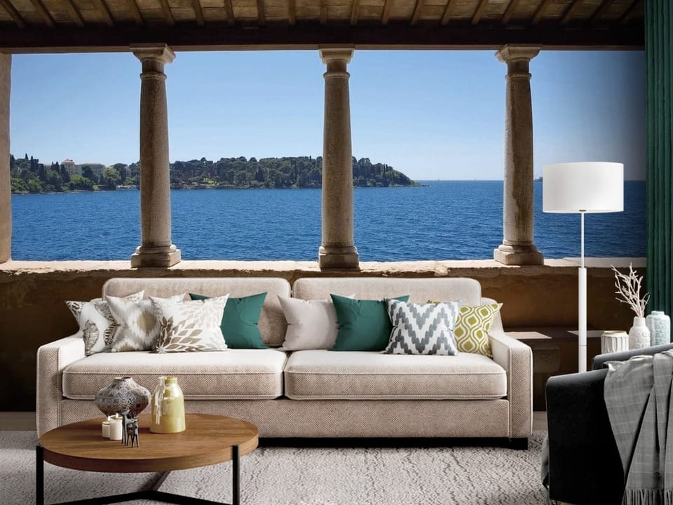 Fototapeta z kamiennymi kolumnami i widokiem na błękitne morze - dekoracja ściany za kanapą w salonie